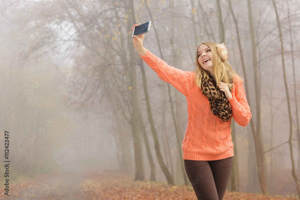 Obraz premium Happy fashion woman in park taking selfie photo.