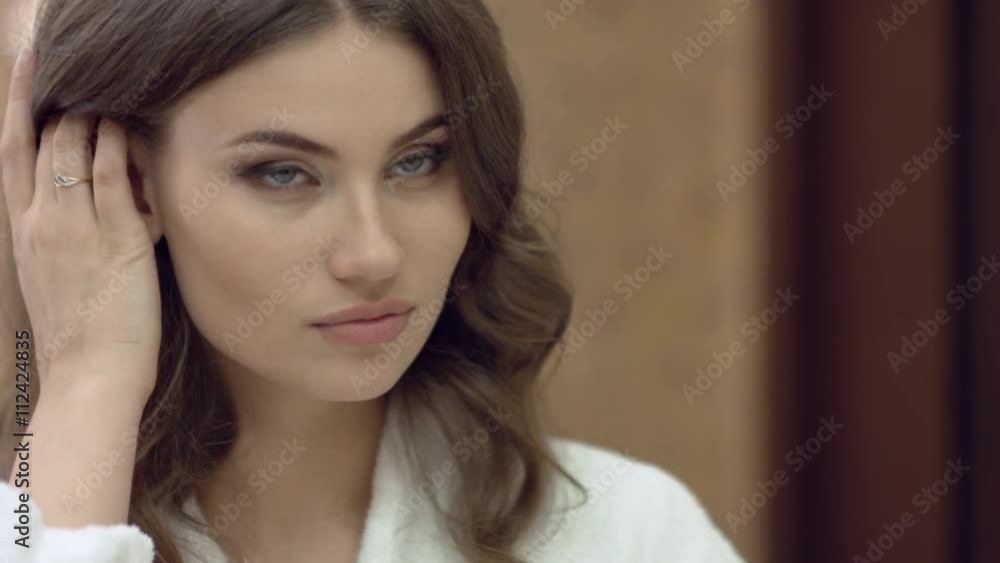 Beautiful woman in the bathrobe standing in the bathroom and brushes her teeth in the morning Beautiful woman in the bathrobe standing in the bathroom and brushes her teeth in the morning