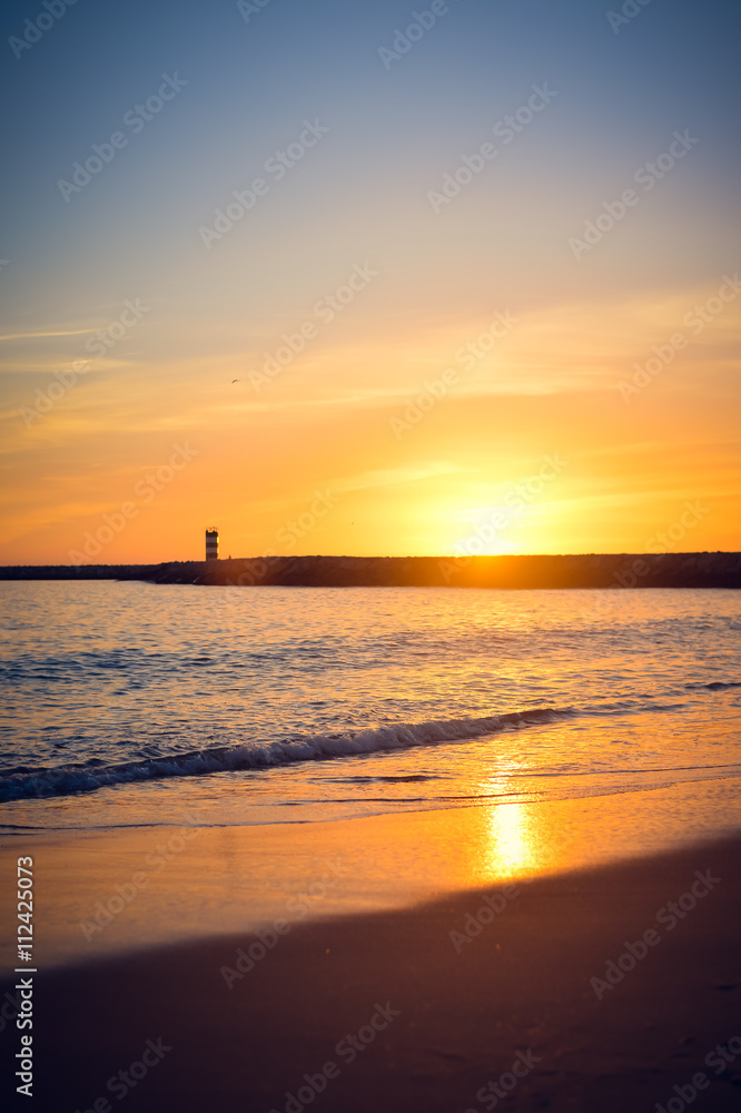 Beautiful golden seascape with a lighthouse at sunset