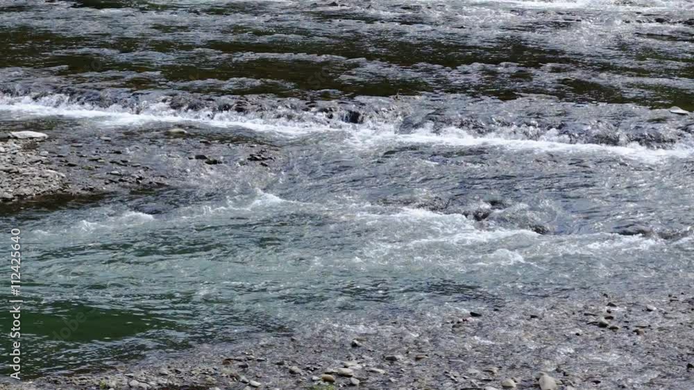 Close up of water stream with white and transparent bubbles, river running through a canyon Close up of water stream with white and transparent bubbles, river running through a canyon