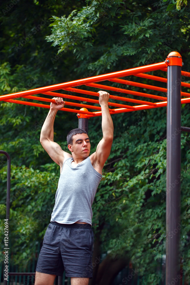 Muscular man doing pull-ups on horizontal bar Muscular man doing pull-ups on horizontal bar