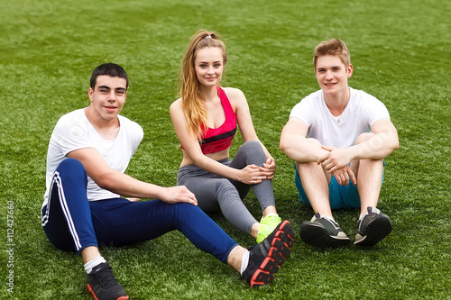 young sport people sitting on the grass