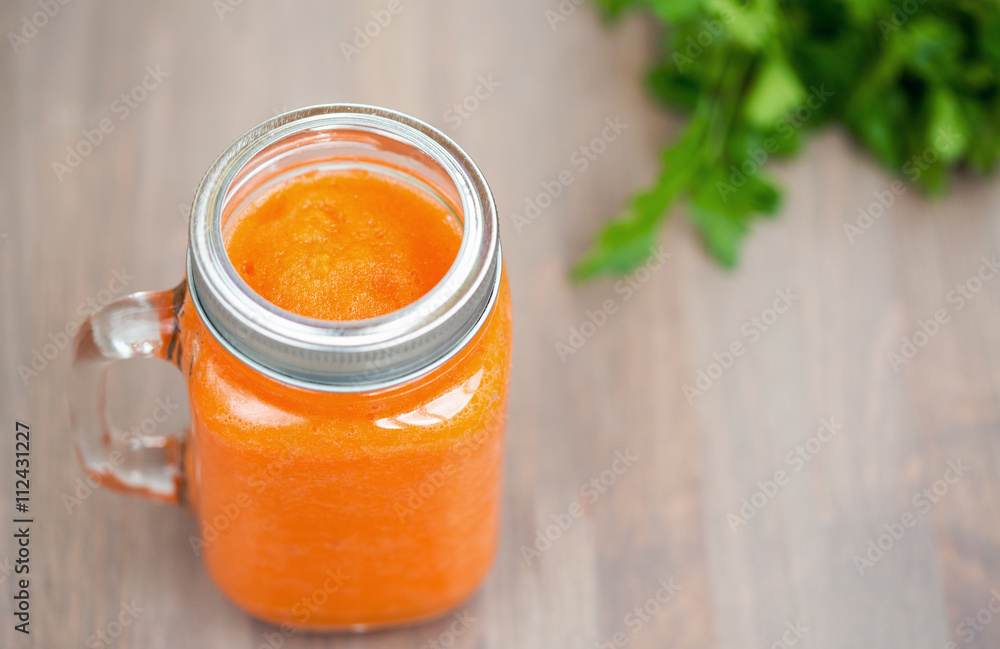 Healthy carrot smoothie in a jar with tube and parsley on wooden background. Shallow dof Healthy carrot smoothie in a jar with tube and parsley on wooden background. Shallow dof