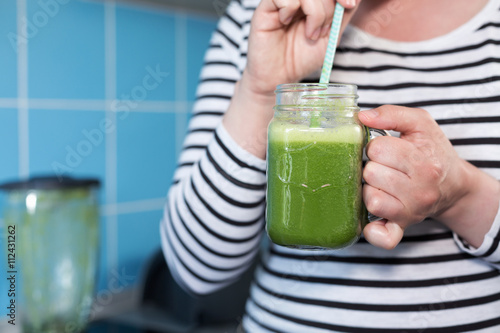 Healthy eating, food, diet, detox concept Female hands with green smoothie and tube