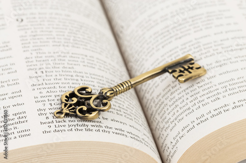 Vintage key on holy bible page concept theology study