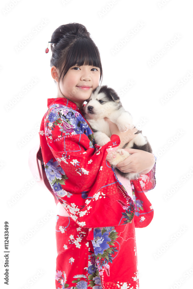 Little asian girl in red kimono playing with a siberian husky pu Little asian girl in red kimono playing with a siberian husky pu