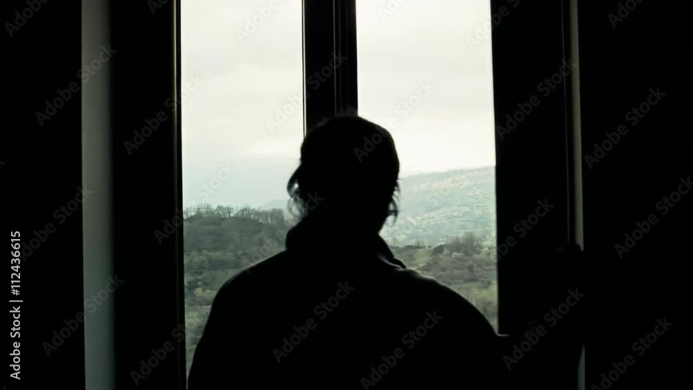 A man opens a window and contemplates the mountainous scenery outside. A man opens a window and contemplates the mountainous scenery outside.