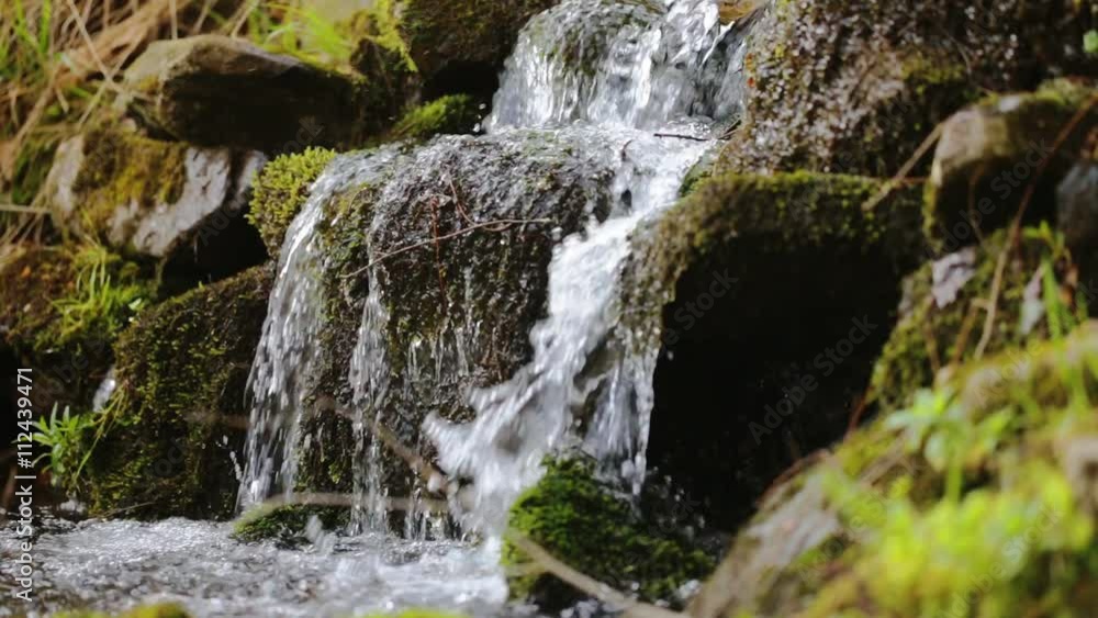 Pure fresh water waterfall in forest with stones and rocks covered by moss Pure fresh water waterfall in forest with stones and rocks covered by moss