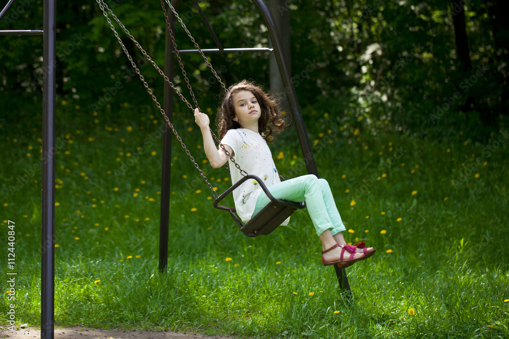 Little girl on a swing in the summer park Little girl on a swing in the summer park
