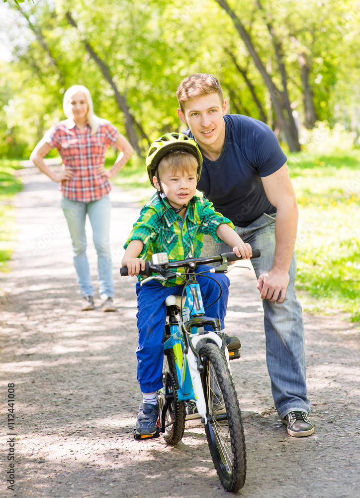 mother and father teaches his son to ride a bike mother and father teaches his son to ride a bike