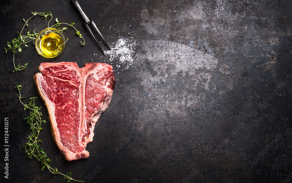 Raw T-bone Steak with fresh herbs and oil on dark rust metal background, top view, place for text, horizontal