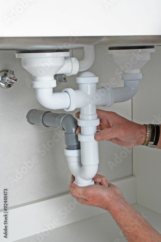 Plumber installing drain pipes under kitchen sink