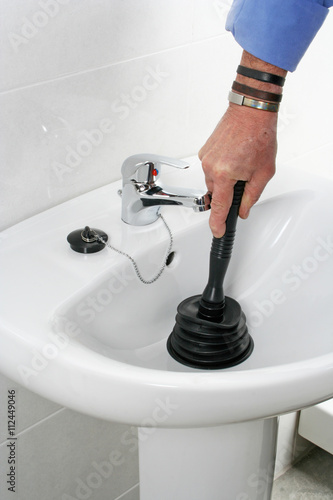 Plumber cleaning clogged washbasin © hansgeel