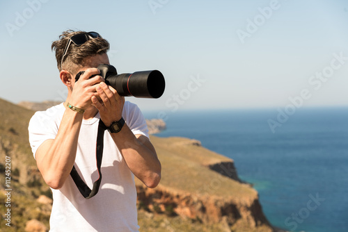 man taking a picture of the landscape against the sea