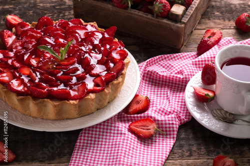 Tart with strawberries and whipped cream on wooden vintage table