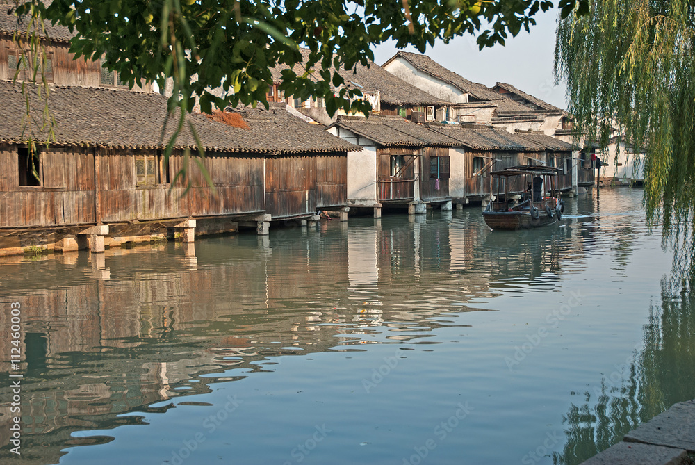 Shanghai, Wuzhen historic scenic town old houses and boat for tourists along a canal. Shanghai, Wuzhen historic scenic town old houses and boat for tourists along a canal.