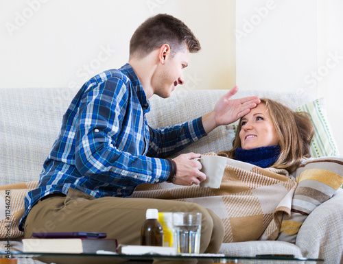 Fotografia woman with cold lying on couch, boyfriend taking care