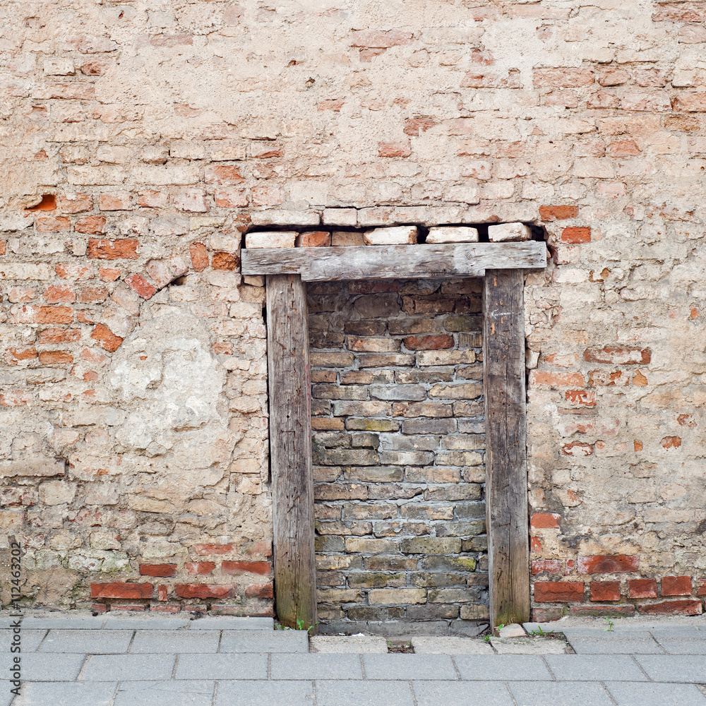 cracked brick wall with bricked up doorway of an abandoned house cracked brick wall with bricked up doorway of an abandoned house