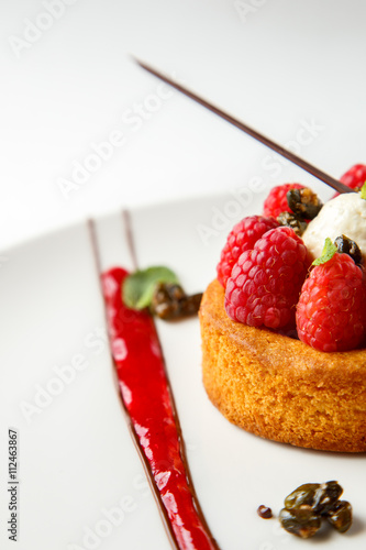 Sable breton or Breton shortbread with vanilla cream and raspberry coulis on white dish photo