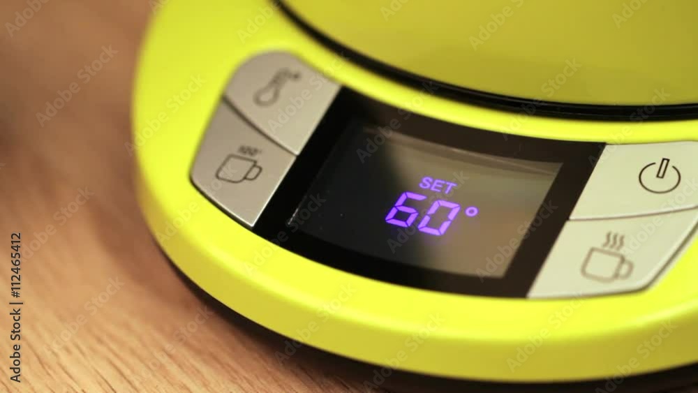 Finger pushing button on a digital thermostat control panel of electric ...