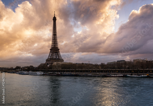 Luminous clouds, Eiffel Tower and the Seine River at sunrise. Port de Suffren, Paris, France