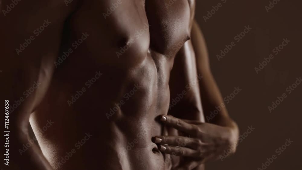 Hands of young woman touching athletic torso with abs of man. Graded Hands of young woman touching athletic torso with abs of man. Graded