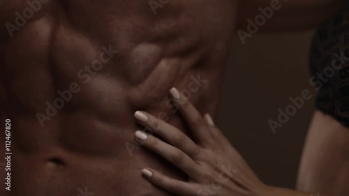 Hands of young woman touching athletic torso with abs of man. Graded