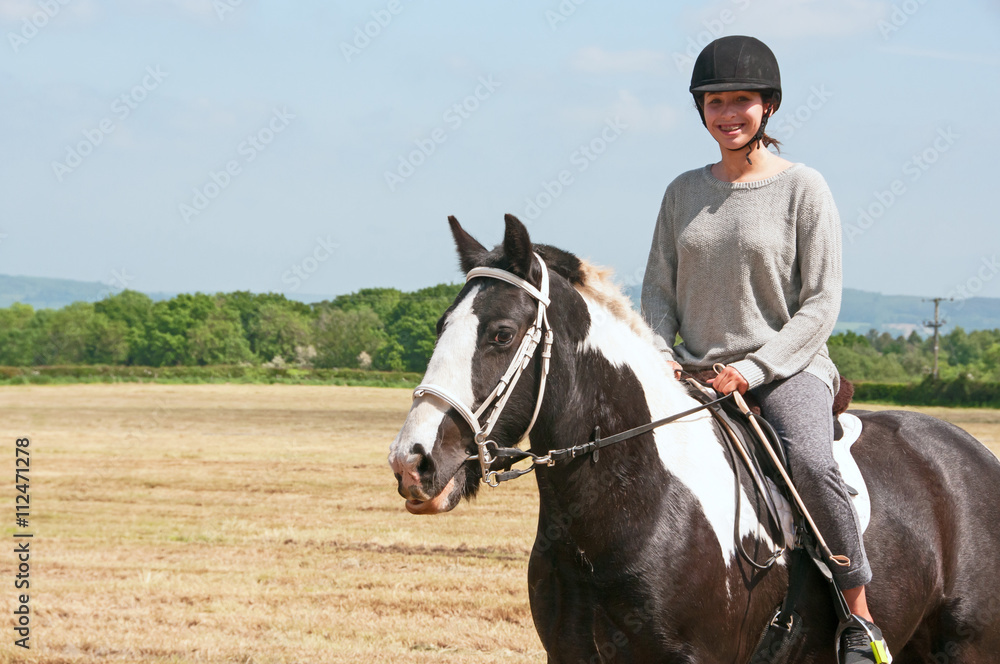 Young rider on her horse in a recently cut crop field