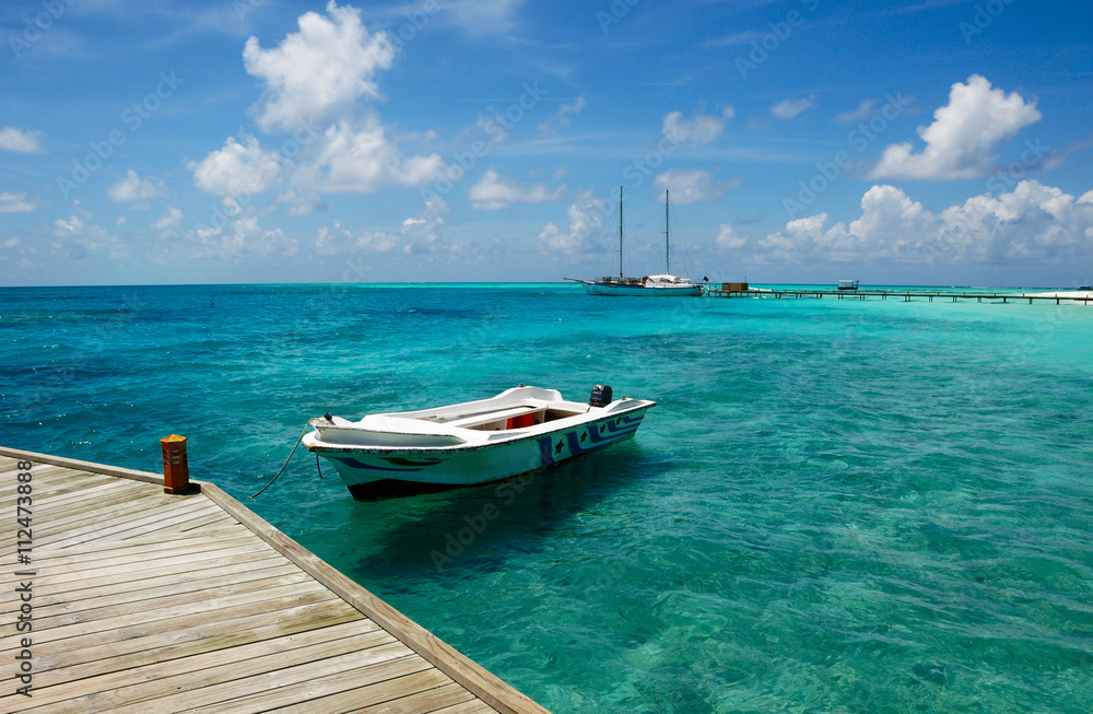 Moored white boat in blue Maldivian lagoon