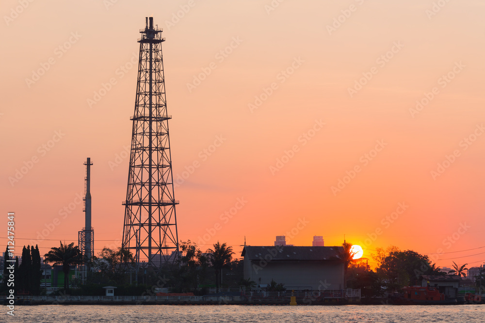 Oil refinery tower during sunrise, heavy industry background