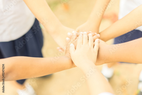 Children making pile of hands  teamwork concept