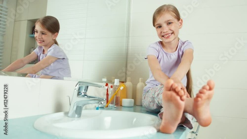 Portrait blonde child girl 7-8 years sitting in the bathroom