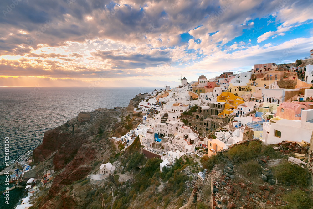 Picturesque view, Old Town of Oia or Ia on the island Santorini, white houses, windmills and church with blue domes at sunset, Greece