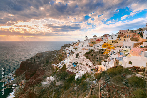 Picturesque view, Old Town of Oia or Ia on the island Santorini, white houses, windmills and church with blue domes at sunset, Greece