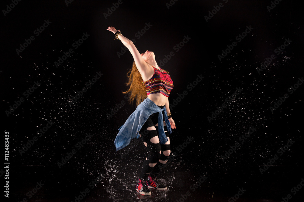 red-haired girl in the style of street dance is dancing on the water and  head raised like a star. studio with black background Stock Photo | Adobe  Stock