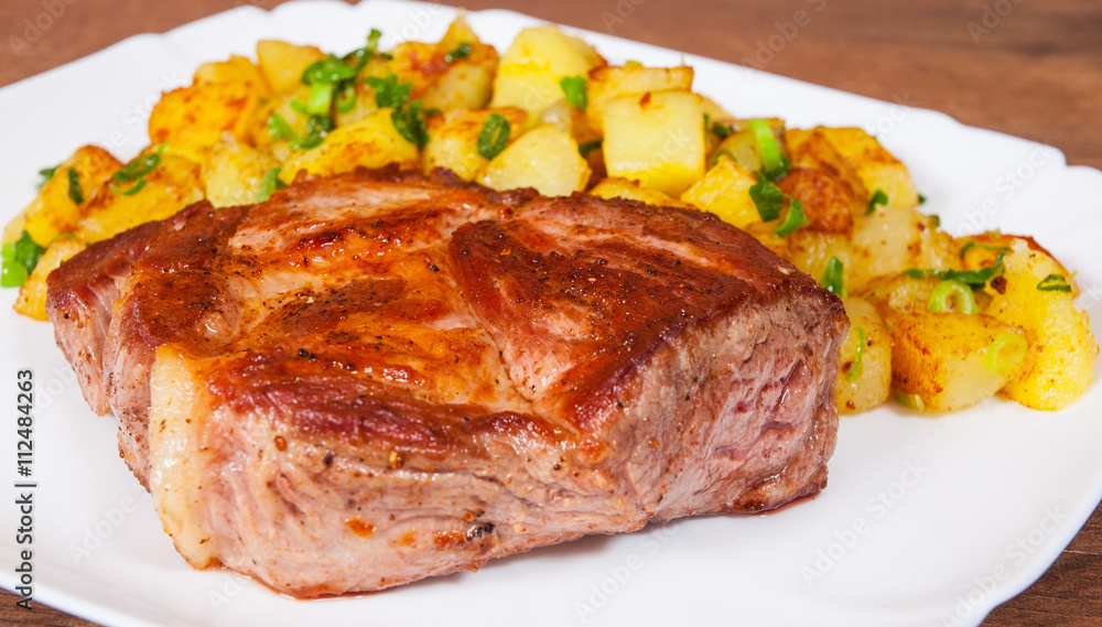 grilled meat fillet steak with fried potato in a plate on wooden table