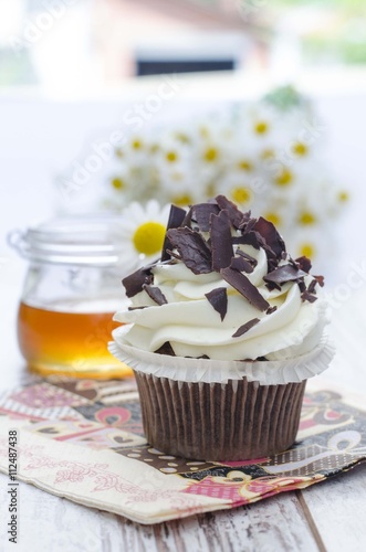Muffin. Cupcake with chocolate and honey and daisy flower.