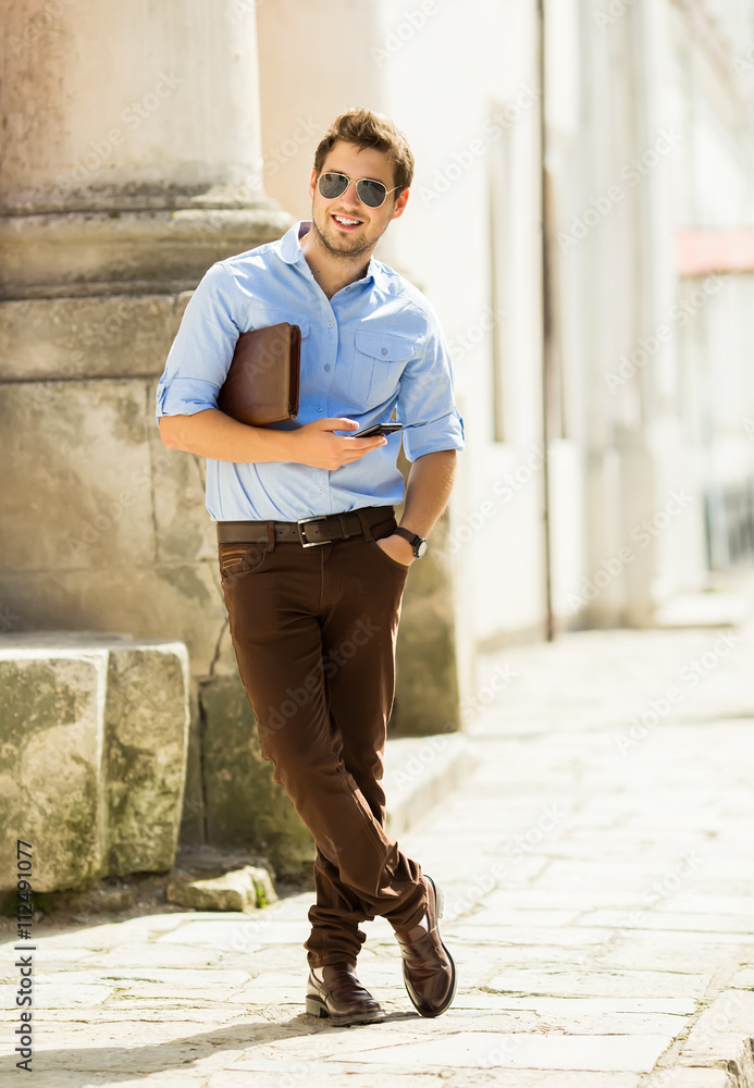 Urban business man talking on smart phone at walking. Handsome male model in his 20s. Urban business man talking on smart phone at walking. Handsome male model in his 20s.