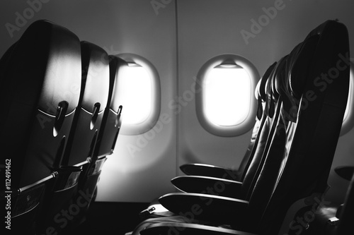 Black and white photo of airplane seat and window inside an aircraft