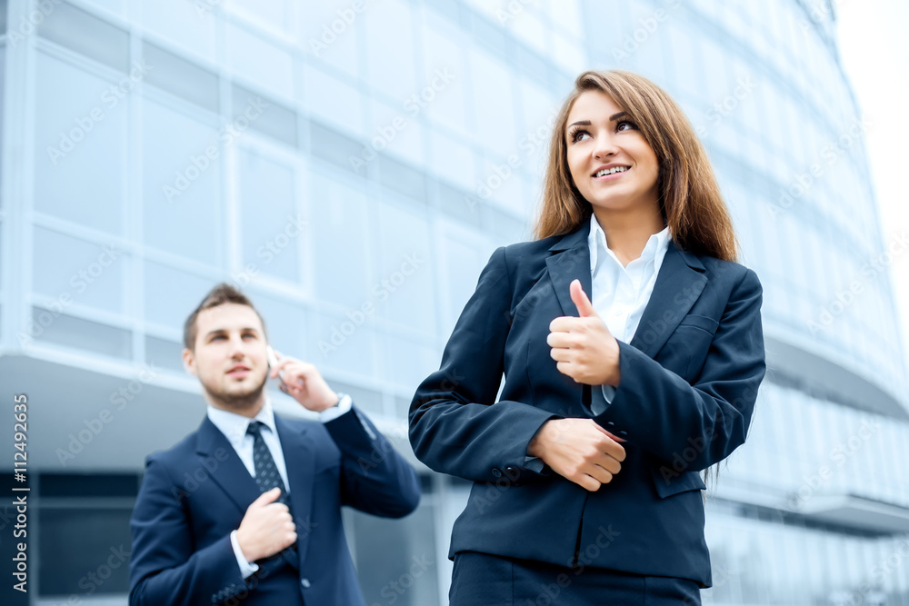 Successful young business woman showing thumbs up sign standing Successful young business woman showing thumbs up sign standing