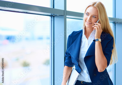 Businesswoman standing against office window talking on mobile phone © lenets_tan