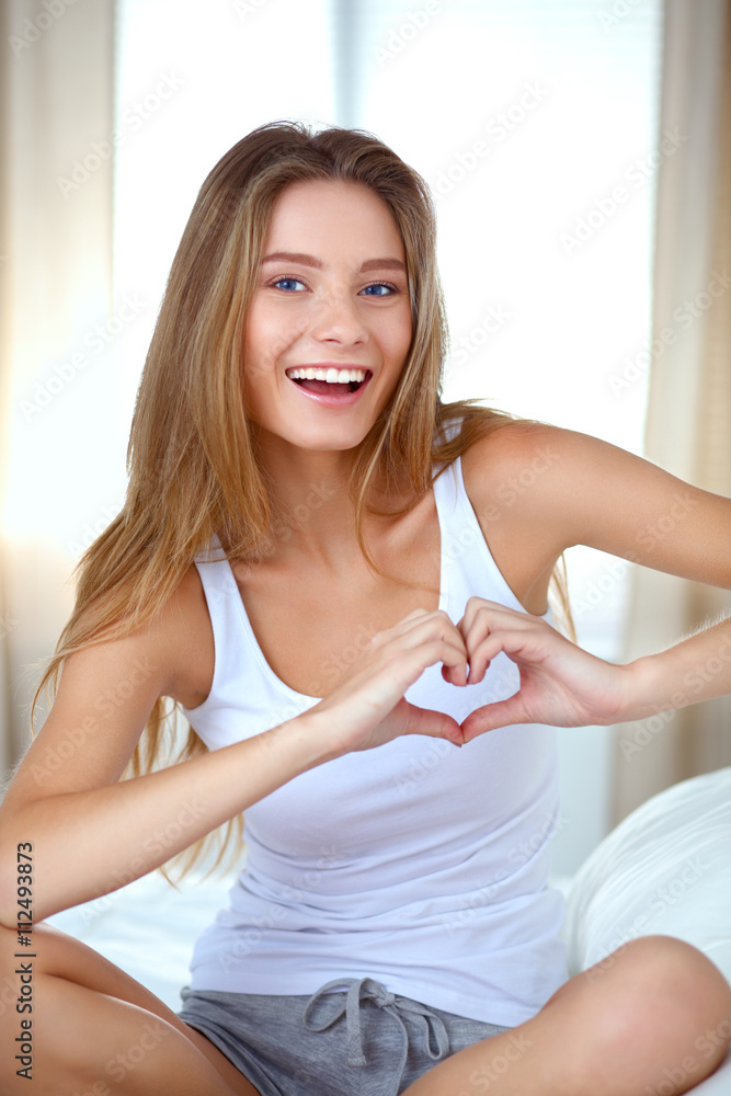 Beautiful woman showing heart shape on her hand , sitting bed - obrazy, fototapety, plakaty 