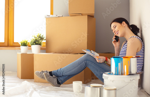 Woman choosing paint colour from swatch for new home sitting on wooden floor © lenets_tan