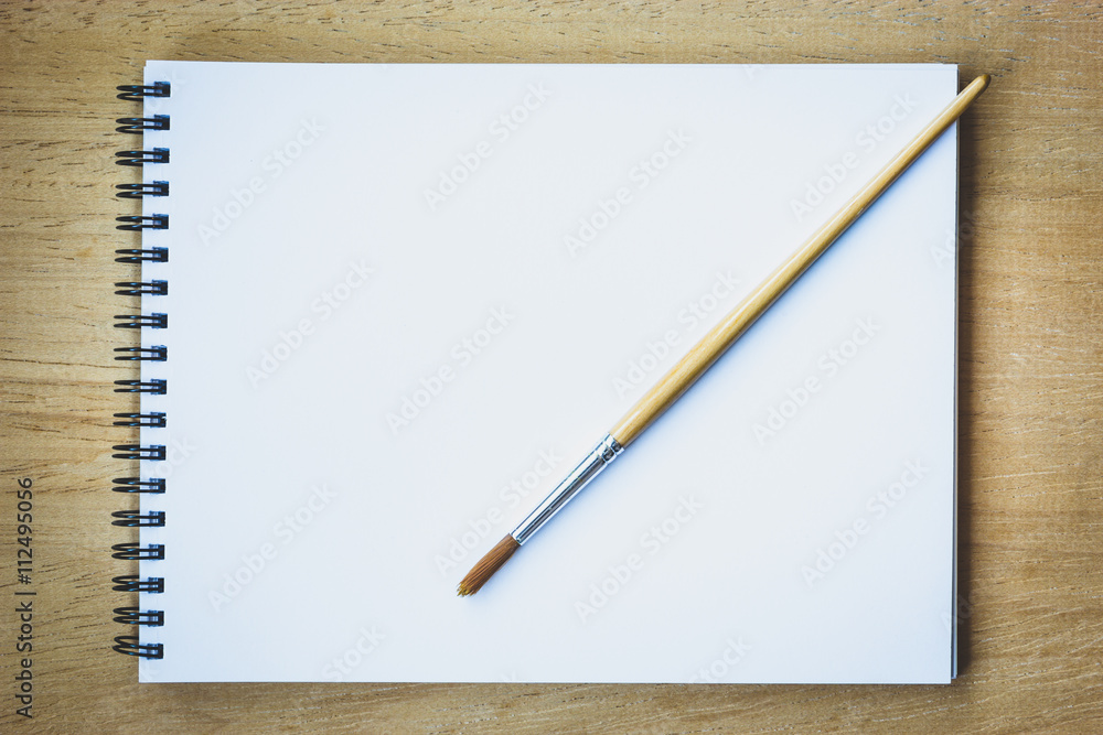 Paintbrush on blank drawing paper book Paintbrush on blank drawing paper book