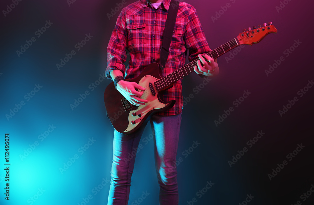 Fototapeta premium Man with guitar on dark foggy background