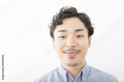 男性 ポートレート 笑み 室内 白バック 髭 パーマ オフィスカジュアル アップ カメラ目線