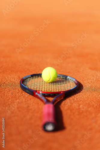 Tennis ball and racket on the court. © jozefklopacka