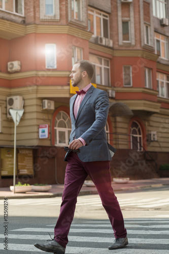 Sytlish businessman in suit walking at city street