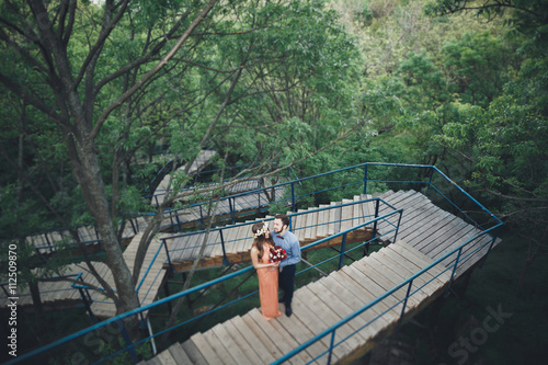 Stylish beautiful happy wedding couple kissing and embracing in Botanical Garden © olegparylyak