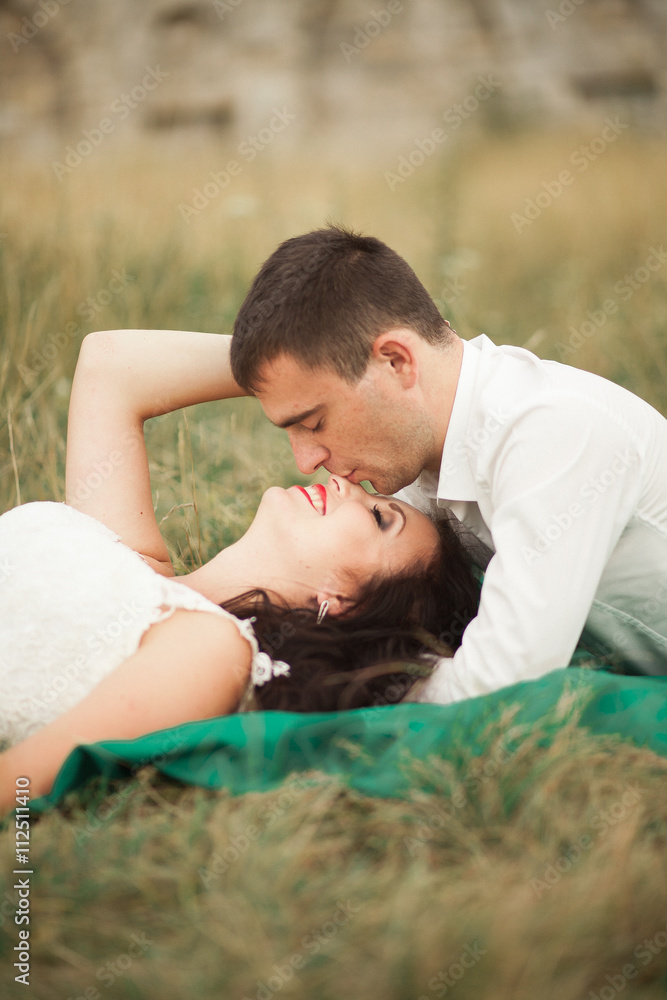 Happy wedding couple lying on green grass at the summer time Happy wedding couple lying on green grass at the summer time